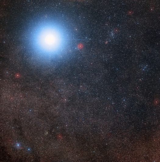 his image of the sky around the bright star Alpha Centauri A B also shows the much fainter red dwarf star, Proxima Centauri, the closest star to the Solar System. The picture was created from pictures forming part of the Digitized Sky Survey 2. The blue halo aroun d Alpha Centauri AB is an artifact of the photographic process, the star is really pale yellow in co lour like the Sun. Credit: Digitized Sky Survey 2 Acknowledgement: Davide De Martin/Mahdi Zamani 